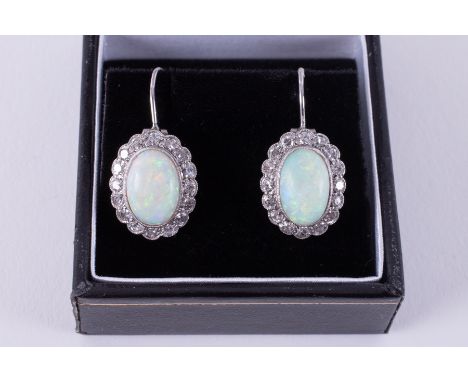 A pair of white gold cluster style drop earrings set with an oval cabochon cut opal, measuring approx. 11mm x 7.5mm x 3.3mm, 