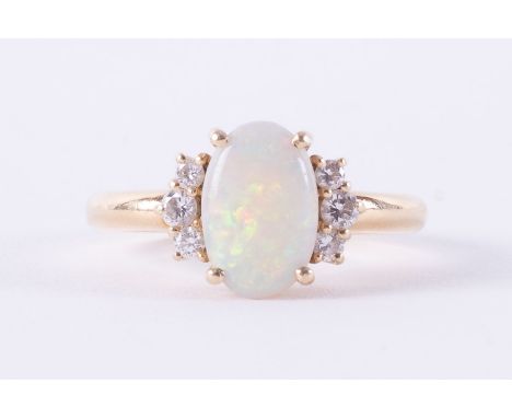 An 18ct yellow gold ring set with an oval cabochon cut opal, measuring approx. 10mm x 6.5mm x 2.2mm, set with three small rou