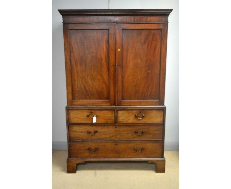 A George III mahogany press, the upper section with dentil cornice above a pair of panel doors enclosing sliding shelves, the