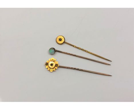 Three gold pins, two marked 15ct and set with diamond and ruby, the other unmarked and set with opal. (3)