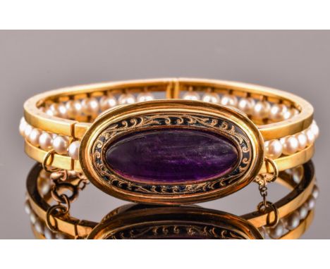 An 18ct yellow gold bangle, set to centre with a cabochon amethyst measuring approximately 26mm x 10mm, surrounded by black e