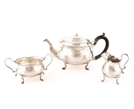 An Edward VII three piece silver teaset, including a teapot with wooden handle, milk jug and sugar bowl, all hallmarked for C