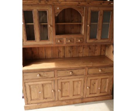 Large modern waxed pine dresser, the raised back with central open shelf above three drawers, flanked by two glazed cupboard 