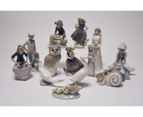 A collection of Nao figures, including a young boy in a shell, a hen with chicks, an owl, a young girl with doves, two models
