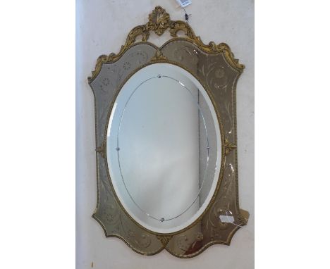 A 20th century wall mirror, gilt frame with Shell finial and scrolling foliate decoration, the oval bevelled plate within flo