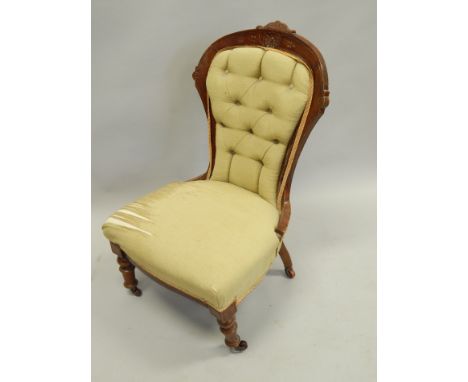 A Victorian walnut show frame nursing chair, with a button padded back and seat, on turned tapering legs, with ceramic castor