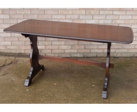 An Ercol style dark elm dining table, the rectangular top with rounded corners, and a moulded edge on end supports, with cent