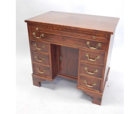 A mahogany kneehole desk, the rectangular top above a brushing slide, and a frieze drawer, with three further short drawers, 