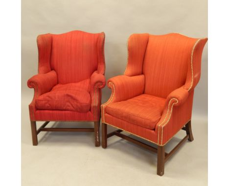 A pair of George III style mahogany wing back chairs, each upholstered in red/orange striped fabric, with brass button border