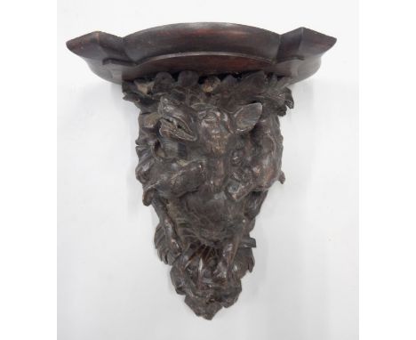 A late 19thC Black Forest type wall bracket, carved in the form of fighting or hunting dogs, with a shaped platform, 42cm hig