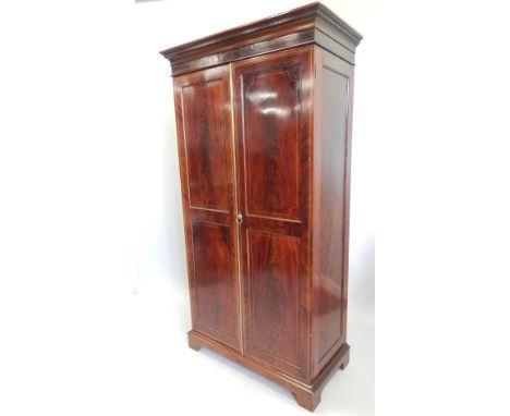 An Edwardian mahogany and box wood strung wardrobe, the top with a dentil cornice above two doors, each with two panels, encl