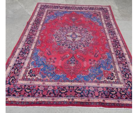 A Persian carpet, with a design of flowers, vases, leaves etc, on a deep red ground with multiply borders, 309cm x 203cm.