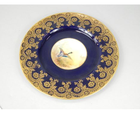 A Royal Worcester cabinet plate, painted centrally with a mallard in flight, unsigned, on a cobalt blue and gilt ground, prin