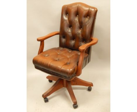 A stained pine office chair, upholstered in brown button leather, with castors. The upholstery in this lot does not comply wi