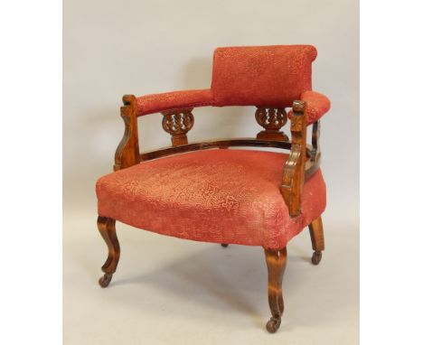 An Edwardian oak tub shaped chair, with a padded back, arm rests and seat, and pierced supports on splayed legs, with ceramic