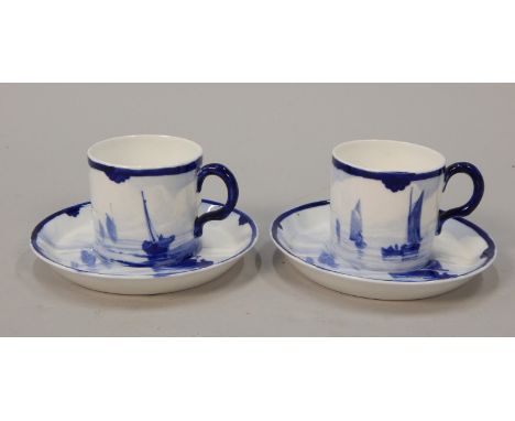 A pair of Royal Crown Derby coffee cans and saucers, each decorated in blue with a coastal scene with ships etc., printed mar