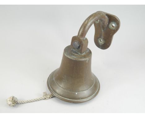 A wall mounted brass bell, with hinged bracket