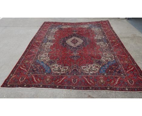 A Persian type carpet, with a design of flowers, scrolls etc, medallions, on a navy and red ground with multiple borders, 397