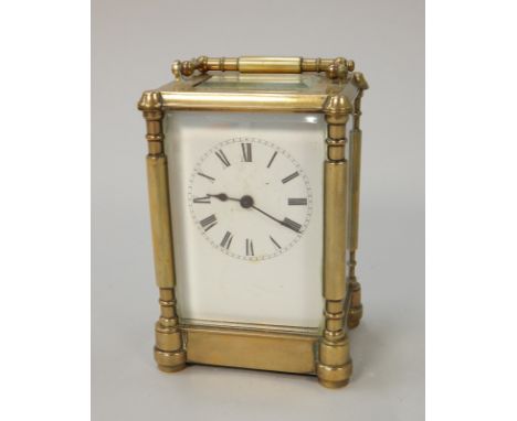 A late 19th/early 20thC French brass carriage timepiece, with a white enamel dial and cylindrical columns, 17cm high