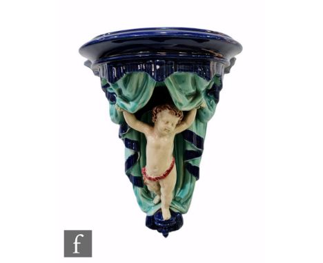 A 19th Century Wedgwood majolica wall bracket modelled as a cherub holding a swagged curtain open, the whole in turquoise and