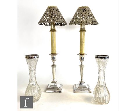 A pair of hallmarked silver candlesticks with square bases below flaring columns and circular scones fitted with later faux c