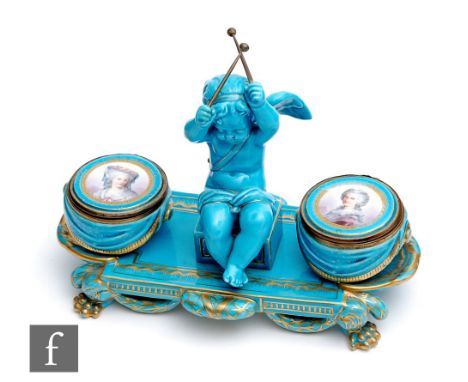 A late 19th to early 20th Century Sevres inkwell modelled as a cherub holding drumsticks, sat beside two lidded pots with dra