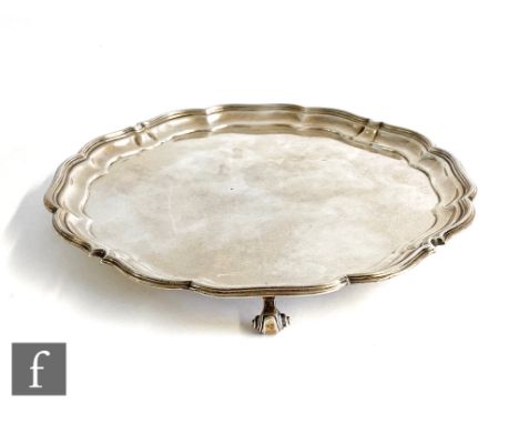 A hallmarked silver circular salver with scalloped borders and raised on four scroll feet, presentation signatures to base, w