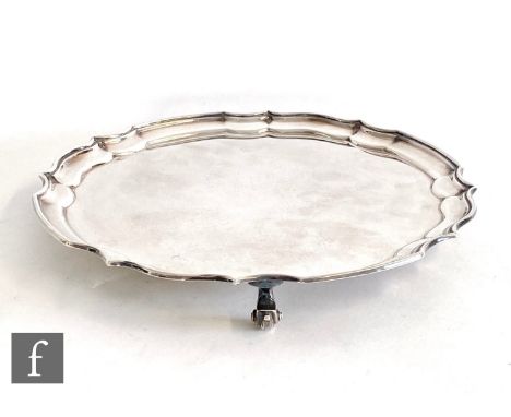 A hallmarked silver circular salver of plain form with scallop border and raised on three scroll feet, weight 15.5oz, diamete