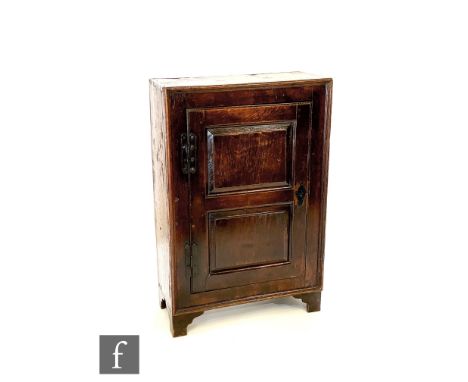 A 19th Century oak hanging cupboard enclosed by a fielded panelled door, on later bracket feet, height 93cm x depth 27cm x wi