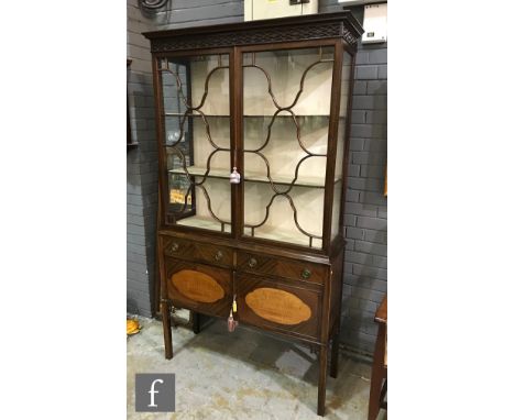 An early 20th Century Chippendale style mahogany side display cabinet, the blind fret-carved pediment above bar glazed doors,