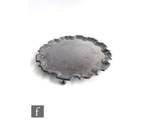 A hallmarked silver circular salver of plain form with scalloped border and raised on three scroll feet, weight 17.5oz, diame