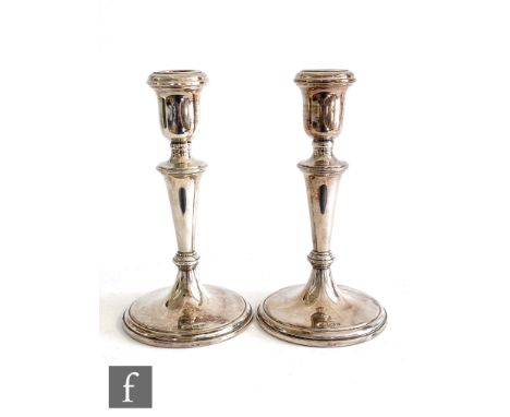 A pair of hallmarked silver candlesticks, circular stepped bases below plain flaring columns and circular sconces, heights 18