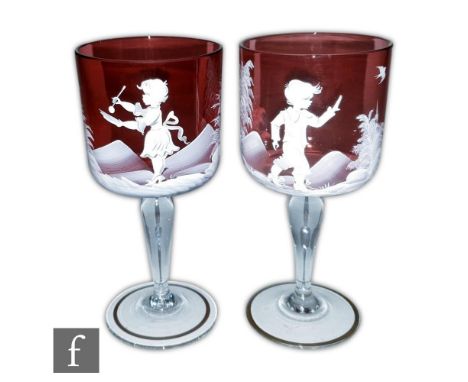 A pair of Mary Gregory style wine glasses with ruby bucket form bowl decorated with a stylised enamel scene of a boy and girl
