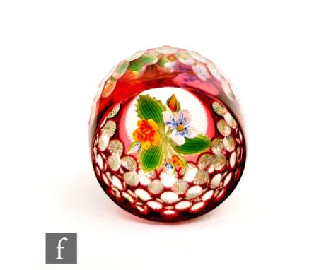 A 20th Century paperweight, internally decorated with lampwork yellow and white flowers, the outside cased in ruby with facet
