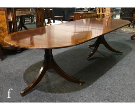 A Regency style rosewood crossbanded D end mahogany dining table with two extra leaves, on ring turned pedestals and splayed 