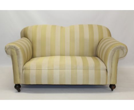 Victorian drop-end twin seater sofa upholstered in gold and beige striped fabric, raised on bun feet and castors