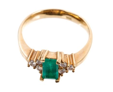 Emerald and diamond ring with a central step cut diamond with three brilliant cut diamonds to each shoulder, in claw setting,