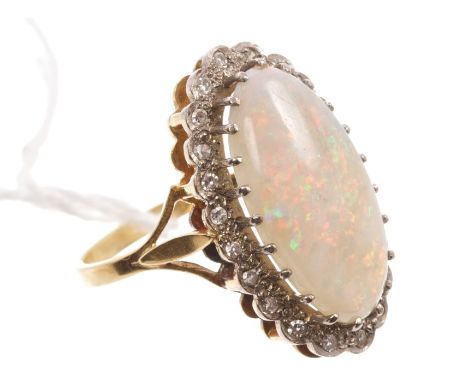Opal and diamond cluster ring, the large oval cabochon opal surrounded by a border of single cut diamonds, on gold (18ct) sha