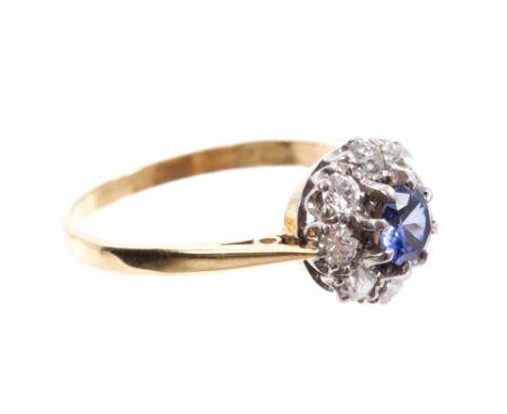 Sapphire and diamond flower-head cluster ring with a circular mixed cut blue sapphire surrounded by a border of eight old cut