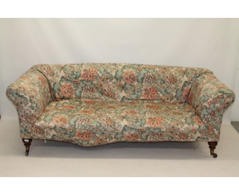 Good late 19th century deep sofa by Howard & Sons, allover fabric upholstered, on turned walnut feet and brass cappings and c