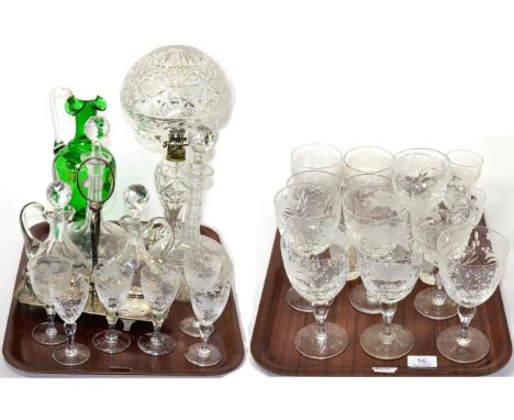 A quantity of engraved wine glasses, tumblers, two decanters, green glass ewer and a cut glass mushroom lamp (on two trays)