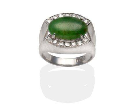 A Jade and Diamond Ring, an oval cabochon jade in a white claw setting between to rows of pavé set eight-cut diamonds, to spl