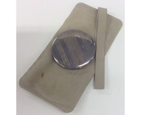 A silver mounted engine turned lady's compact contained within a leather case. Approx. 95 grams. Est. £20 - £30.