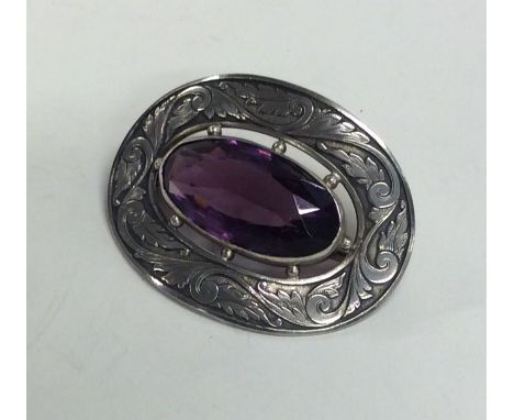 An oval silver brooch decorated with an amethyst. Approx. 27 grams. Est. £20 - £30.
