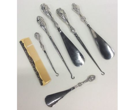 A silver mounted button hook and a shoe horn, together with others. Approx. 400 grams. Est. £20 - £30.