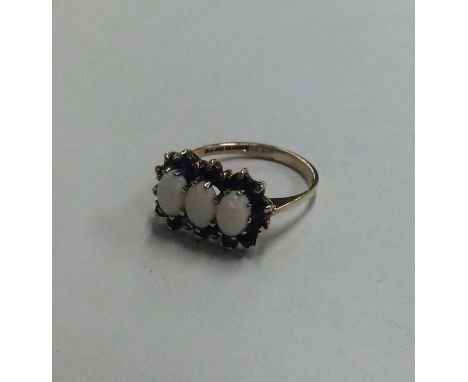 An opal and sapphire triple cluster ring in 9 carat mount. Approx. 2.2 grams. Est. £40 - £60.