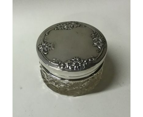 A circular silver and glass dressing table jar decorated with flowers. Est. £10 - £20.