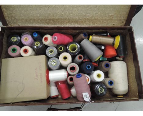 A vintage suitcase containing a large selection of industrial sewing thread.