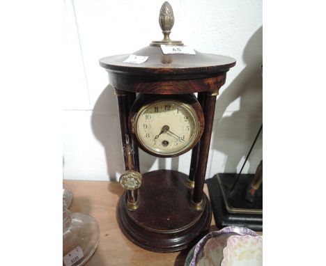 A vintage treen mantle clock with raised column enamel face and brass fitments
