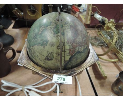 A lamp in the form of a globe with brass effect base